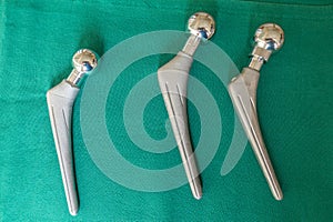 Some explanted hip prostheses lie spread out on a green surgical drape