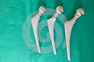 Some explanted hip prostheses lie spread out on a green surgical drape