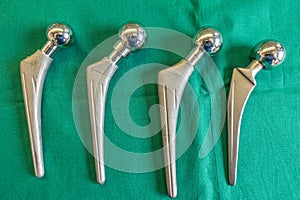 Some explanted hip prostheses lie spread out on a green surgical drape