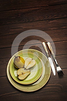 Some fresh pears on green circular plates with vintage style cutler