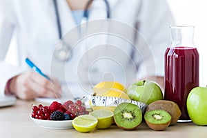 Some fruits such as apples, kiwis, lemons and berries on nutritionist table.