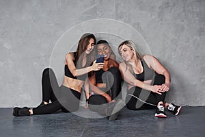 Some funny internet content. Group of multi ethnic women sitting in the studio against grey background