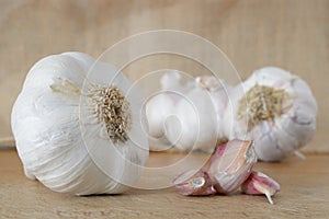 Some garlic wholes and cloves on a wooden table in a rustic kitchen.