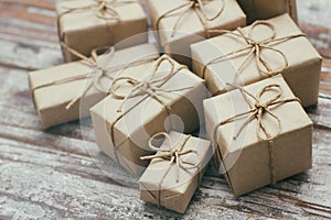 Some gift boxes wrapped in brown craft paper and tie hemp cord. Decorative wooden background. Your text space. Set of presents.