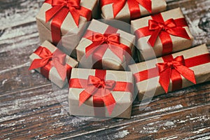 Some gift boxes wrapped in brown craft paper and tie red satin ribbon. Decorative wooden background. Your text space.