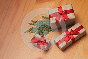 Some gift boxes wrapped in brown craft paper and tie red satin ribbon. Decorative wooden background. Your text space.