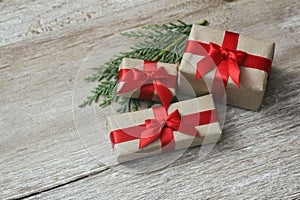 Some gift boxes wrapped in brown craft paper and tie red satin ribbon. Decorative wooden background. Your text space.