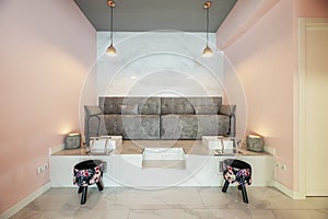 Some gray sofas on a raised platform with sinks and seats for pedicures in a beauty salon