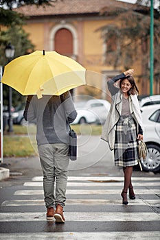 Some handsome and elegant young woman and man pass each other at a pedestrian crossing on a rainy day. Walk, rain, city