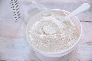 Some milk powder served with a scoop while preparing a baby bottle.