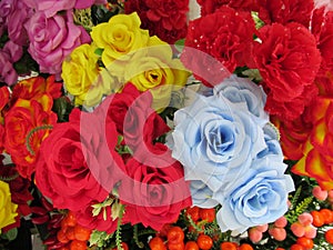 Some multiple colored artificial rose flowers on display for sale