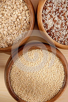 Some oatmeal, millet, rice are in woody bowls.