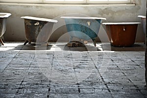 Some old used bathtubs lined up in an industrial ruin building