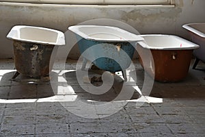 Some old used bathtubs lined up in an industrial ruin building