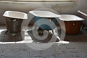 Some old used bathtubs lined up in an industrial ruin building photo