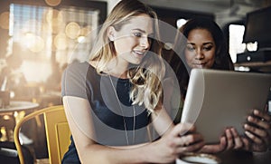 Some online stalking is what we do best. girlfriends sharing something on a digital tablet while sitting in a cafe.