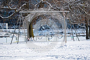 Some playground swings covered in snow .