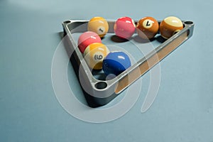 Some pool balls in the metal triangle ball rack on pool table