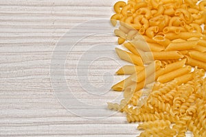 Some raw penne macaroni on a wooden rustic table. Healthy food.