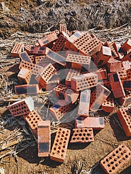 Some red hollow bricks stacked in a haystack