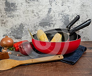 Some of red pans and a apron and a spoon