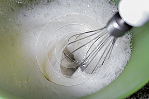 Some rods assembling some egg whites in a yellow bowl. photo