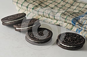 Some round chocolate biscuits still intact with white cream and a napkin