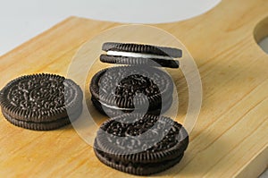 Some round shaped chocolate biscuits with white cream on a wooden board