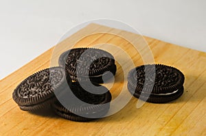 Some round shaped chocolate biscuits with white cream on a wooden board