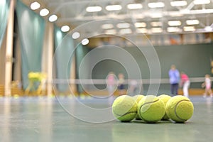 Some tennis balls on tennis court in sports hall,