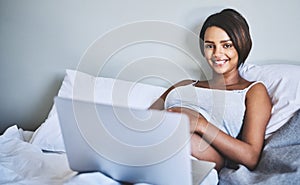 Some time to myself at last. Portrait of a cheerful pregnant woman lying on a bed at home relaxing while browsing on a