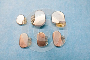 Some various pacemakers and implantable defibrilators lie on a light blue base