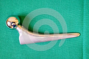 Some various surgical implants made of steel and titanium lie on a green surgical drape