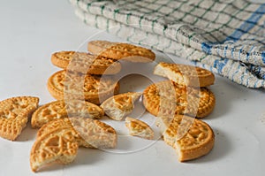 Some whole and broken coconut-flavored round biscuits and a napkin