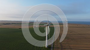 some wind turbines in a green field with the ocean and grass