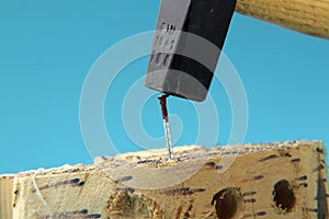 A some worker using hammer to slamming the nail to wooden board.