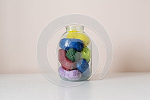 the some yarn rolls of different color put inside the glass bank at home, creative storage sollution