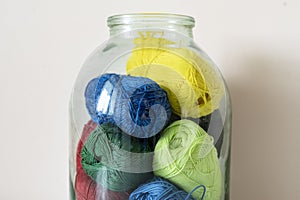 the some yarn rolls of different color put inside the glass bank at home, creative storage sollution