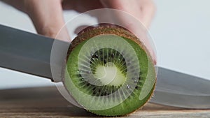 Somebody cutting kiwi with knife, close up. Macro shot