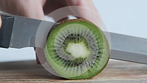 Somebody cutting kiwi with knife, close up. Macro shot