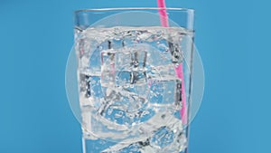 Somebody mix cold water drink with drinking straw sparkling soda blue background
