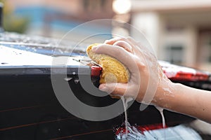 Someone hand catch old yellow sponge washing car spoiler