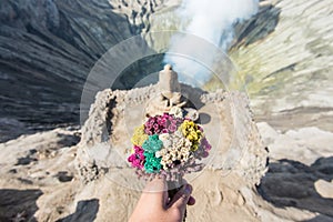 Someone hand holding flowers for praying and offering to Ganesha statue the Hindu god located on Mt.Bromo.