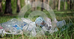 Someone throws a glass bottle into a pile of garbage in the forest