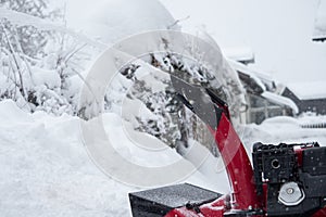 Someone uses a snowthrower outdoors in winter while it is snowing