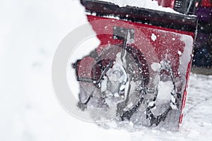 Someone uses a snowthrower outdoors in winter while it is snowing photo