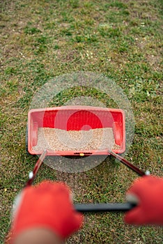 someone using an iron rake to lay grain in a red wagon