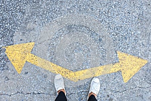 Someone wearing sneakers choosing a waymarked with direction arrows choices left or right.