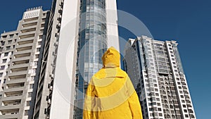 Someone in yellow raincoat staying in front of modern residential area building