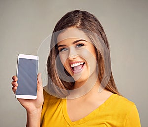 This is something you should definitely have on your smartphone. an attractive young woman holding a cellphone with a